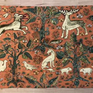 May include: A tapestry featuring a medieval-style design with a lion, deer, unicorn, and other animals on a red-orange background. The tapestry is woven with intricate details and features a variety of green and brown foliage.
