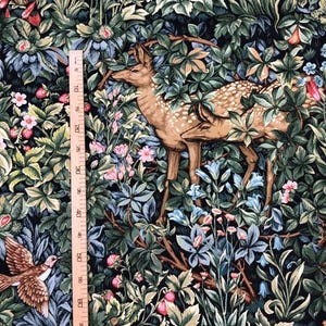 May include: A tapestry fabric with a dark green background featuring a deer, a bird, and various flowers and leaves. The fabric is printed with a detailed design that resembles a traditional tapestry.