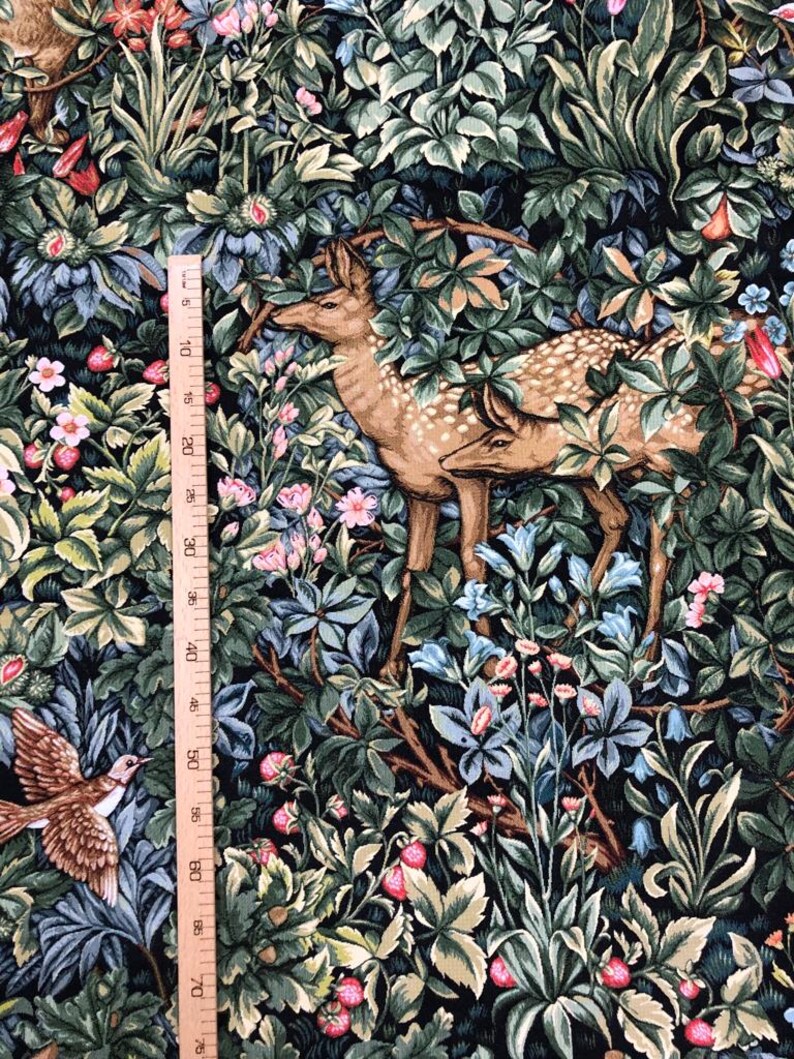 May include: A tapestry fabric with a dark green background featuring a deer, a bird, and various flowers and leaves. The fabric is printed with a detailed design that resembles a traditional tapestry.