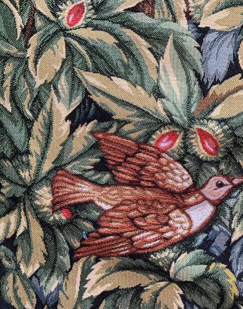 May include: A tapestry featuring a brown bird with white markings flying through a forest scene. The background is a dark green and brown tapestry with leaves and flowers.