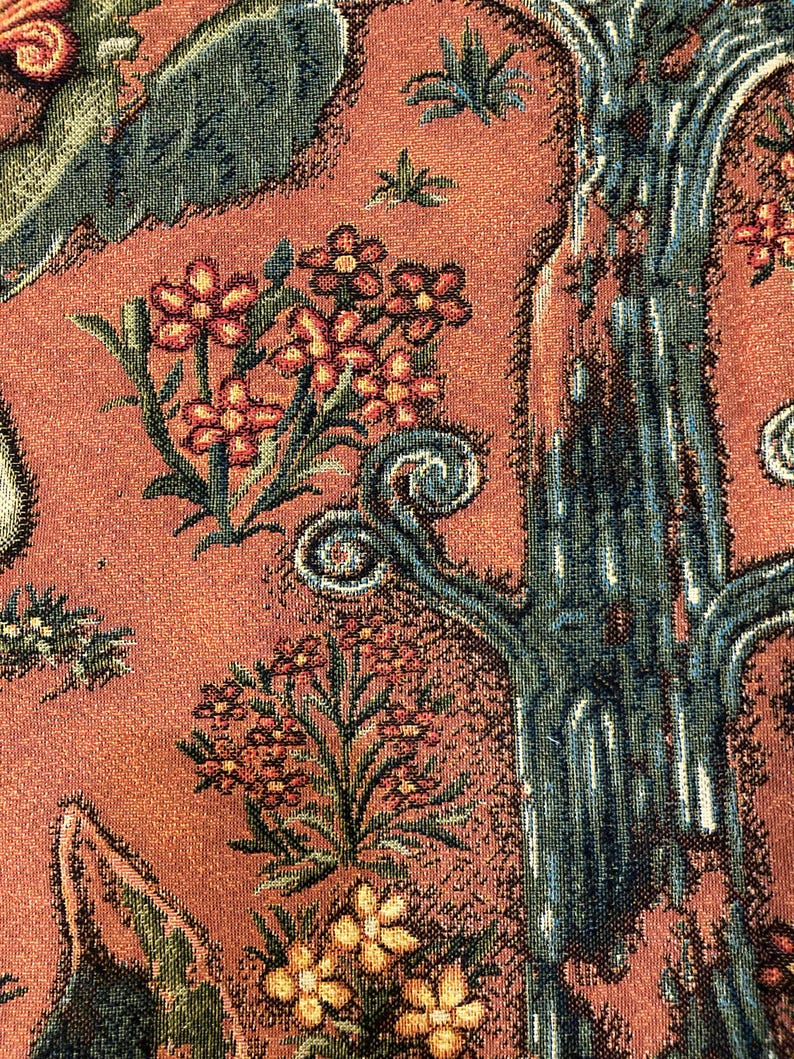May include: Close-up of a tapestry with a detailed design of a tree with a textured bark, green leaves, and red flowers. The background is a reddish-brown color.