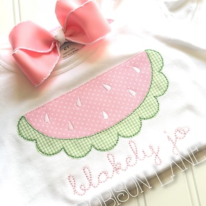 May include: A white t-shirt with a pink and green watermelon applique and the text "blakely Jo ROBISON LANE" embroidered on the front.