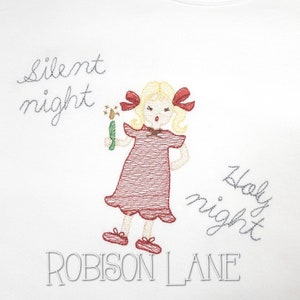May include: Embroidered white fabric with a girl holding a wand and the text "Silent night" and "Holy night" in grey thread. The text "ROBISSON LANE" is also embroidered in grey thread.