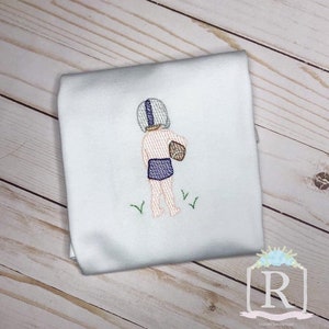 May include: White embroidered t-shirt with a design of a child wearing a football helmet and holding a football. The child is wearing blue swim trunks and is standing on green grass.