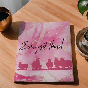 Puede incluir: Un cuaderno rectangular con un fondo de mármol rosa y blanco con vetas de color dorado. La portada muestra una silueta de cinco ovejas y el texto cursivo negro Ewe got This! impreso en el centro de la parte frontal.