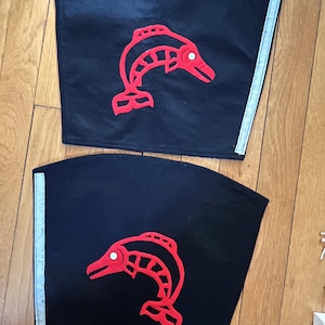 May include: Two black fabric arm bands with red stylized salmon designs. The bands have a white reflective strip on the side.