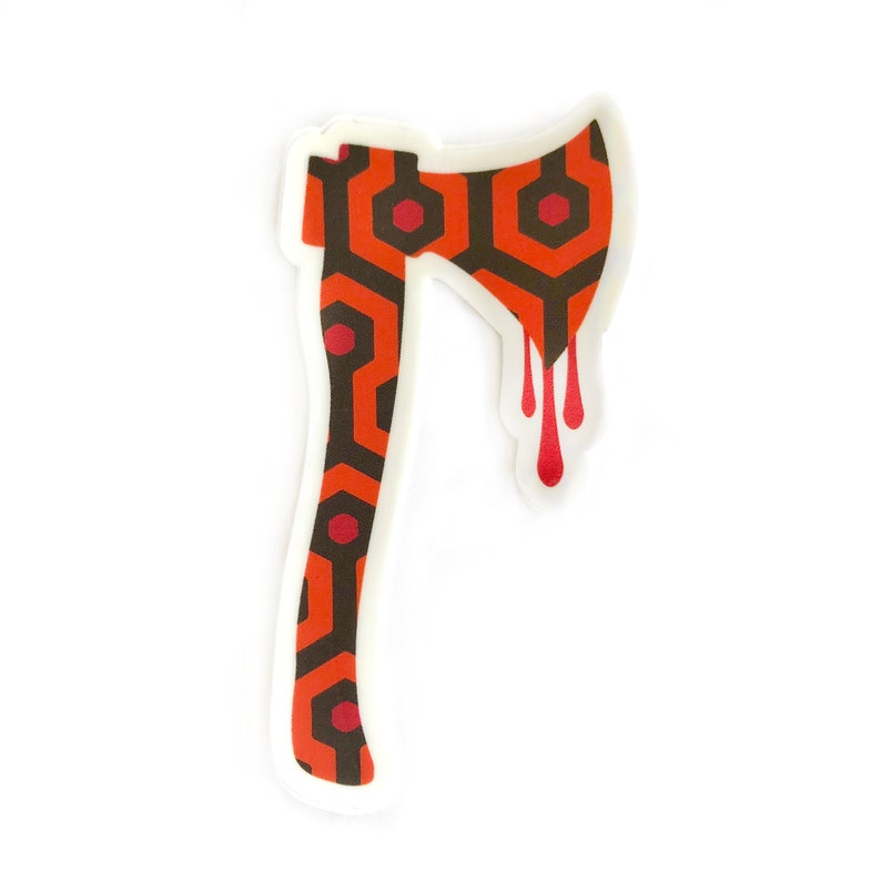 May include: A sticker of an axe with a red and brown geometric pattern, dripping with red paint. The pattern is reminiscent of the carpet from the movie "The Shining".