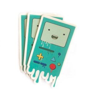May include: Three turquoise blue stickers with a cartoon robot face and buttons. The robot face is dripping with colorful paint.
