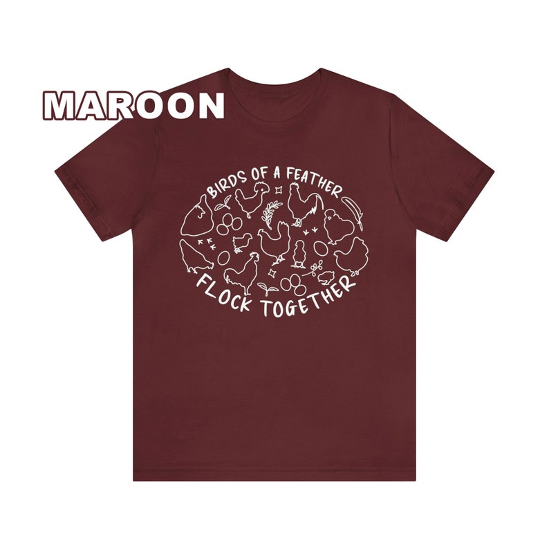 K&ouml;nnte beinhalten: Ein maroonfarbenes T-Shirt mit einer wei&szlig;en Grafik von H&uuml;hnern und dem Text "Birds of a feather flock together".