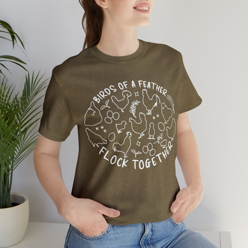 K&ouml;nnte beinhalten: Ein gr&uuml;nes T-Shirt mit einer wei&szlig;en Grafik von H&uuml;hnern und Eiern. Die Grafik lautet "Birds of a feather flock together".