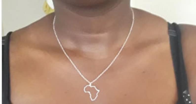 May include: A silver necklace with a pendant shaped like the outline of the continent of Africa.