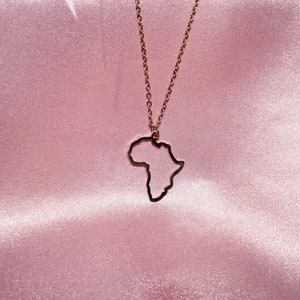 May include: A gold necklace with an outline of the continent of Africa as the pendant.