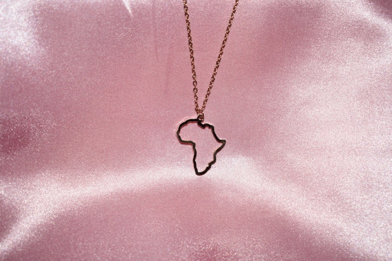 May include: A gold necklace with an outline of the continent of Africa as the pendant.