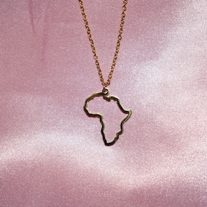 May include: A gold necklace with a pendant shaped like the outline of the continent of Africa.