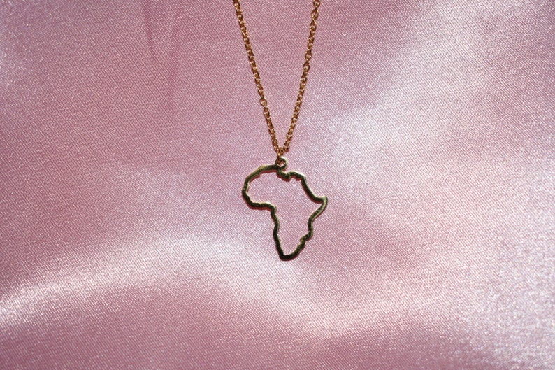 May include: A gold necklace with a pendant shaped like the outline of the continent of Africa.