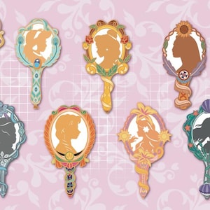 Peut inclure: Une collection de onze broches en forme de miroirs à main décoratifs avec des cadres ornés et des silhouettes de personnages. Chaque miroir présente une palette de couleurs unique et des détails complexes. Le texte ART OF BOX est visible.