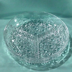 May include: A clear glass divided serving dish with a decorative starburst pattern. The dish has three sections.