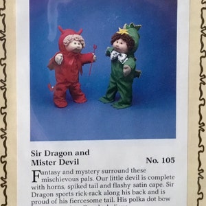 May include: A vintage Cabbage Patch Kids sewing pattern featuring a red devil and a green dragon costume. The pattern is titled "Sir Dragon and Mister Devil" and is numbered 105. The pattern is by Sunny Designs.