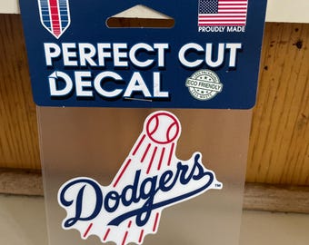 May include: A white sticker with a blue and red Los Angeles Dodgers logo. The sticker says "Perfect Cut Decal" and "WinCraft/MLB".