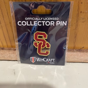 May include: Officially licensed collector pin featuring the USC Trojans logo. The logo is a red and gold "SC" on a navy blue background. The pin is made by WinCraft, by Fanatics.