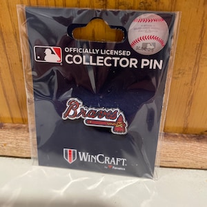 May include: Officially licensed collector pin featuring the Atlanta Braves logo with a red, white, and blue baseball bat and the team name "Braves" in red lettering. The pin is on a blue background with the text "Officially Licensed Collector Pin" and "WinCraft by Fanatics".