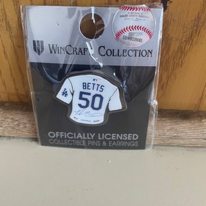 May include: A silver baseball jersey pin with the number 50 and the name Betts on it. The pin is on a black background with the text "Officially Licensed Collectible Pins & Earrings" and "WinCraft Collection".