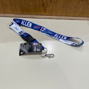 May include: A blue and white lanyard with the name "Josh Allen" and the number "17" printed on it. The lanyard has a black clip and a silver key chain.