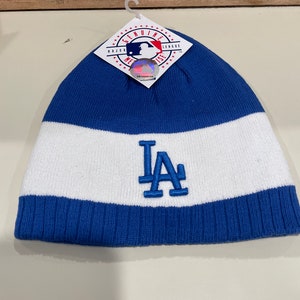 May include: Blue and white knit beanie with the Los Angeles Dodgers logo in blue embroidery. The beanie has a tag that reads "Genuine Major League Merchandise".