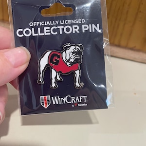 May include: Officially licensed collector pin featuring a white bulldog wearing a red jersey with a white "G" on the front. The pin is on a black background with the text "WinCraft by Fanatics".