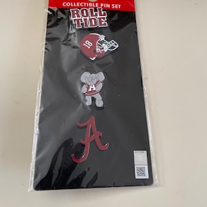 May include: A set of three collectible pins featuring the University of Alabama's mascot, the elephant, and the team's logo. The pins are red and white and have the words "Roll Tide" on the packaging.