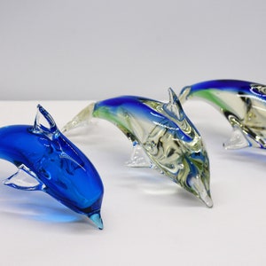 Three beautiful blown glass dolphins with blue, green and clear colors.