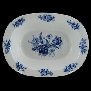 Könnte beinhalten: Ovale weiße Servierplatte mit blauen Blumenmustern. Die Platte hat ein zentrales Bouquet und kleinere florale Akzente am Rand. Die Blumen umfassen Tulpen und andere detaillierte botanische Illustrationen.
