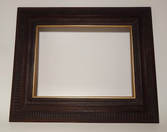 May include: A rectangular, dark brown picture frame with a gold inner border. The frame has a detailed, textured pattern around the edges. The frame is empty, with a white background visible inside.