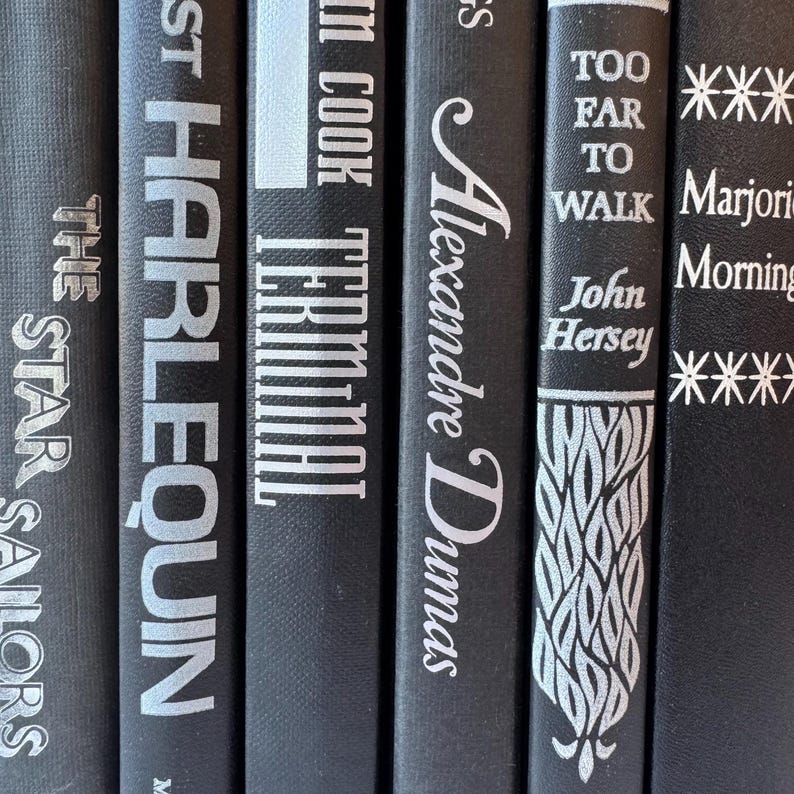 May include: A set of six black hardcover books with silver lettering on the spines. The titles are "The Star Sailors", "Harlequin", "Terminal", "Alexandre Dumas", "Too Far To Walk", and "Marjorie Morningstar".