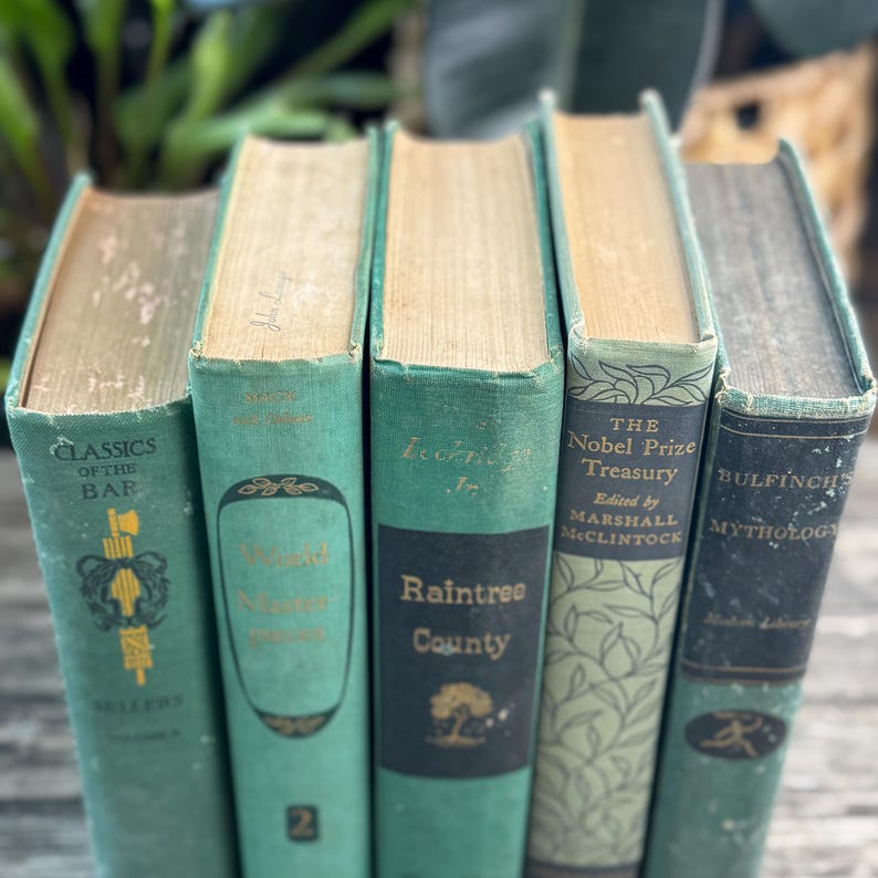 Puede incluir: Una colecci&oacute;n de cinco libros antiguos con cubiertas verde azulado y p&aacute;ginas amarillentas envejecidas. Los t&iacute;tulos incluyen "Classics of the Bar", "Raintree County" y "The Nobel Prize Treasury". Los libros est&aacute;n colocados uno al lado del otro.