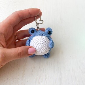 May include: A blue crocheted frog keychain with white accents and a silver heart-shaped ring.