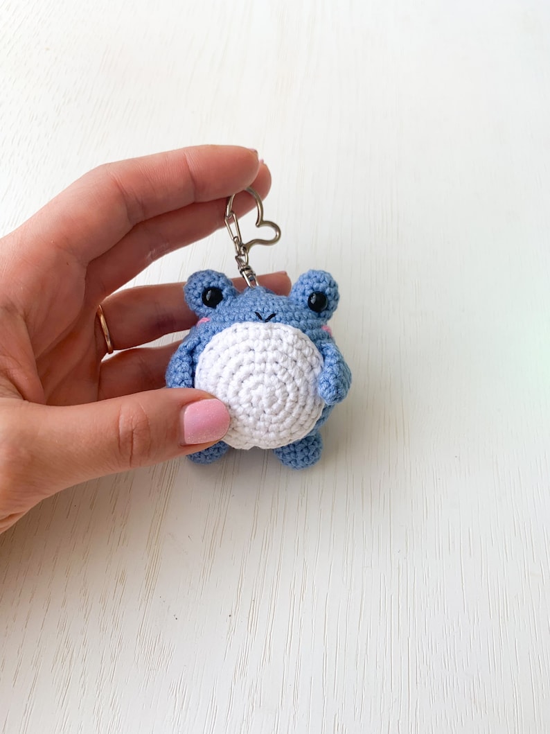 May include: A blue crocheted frog keychain with white accents and a silver heart-shaped ring.