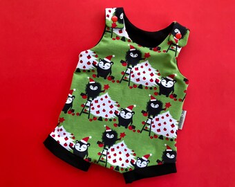 Puede incluir: Romper verde para bebé con un estampado navideño. El diseño presenta osos negros con gorros de Papá Noel, decorando árboles de Navidad con adornos y estrellas rojas. Ribete negro y botones rojos.