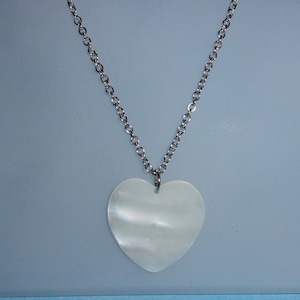 May include: A silver chain necklace with a white heart-shaped pendant.