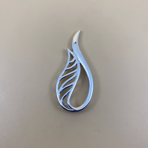 May include: A silver pendant in the shape of a stylized leaf with a delicate, openwork design.