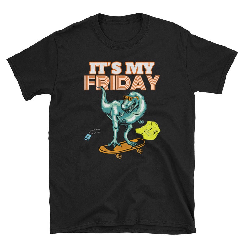Op de afbeelding: Zwart T-shirt met een cartoon dinosaurus met een zonnebril op een skateboard. De tekst "IT'S MY FRIDAY" staat in oranje en wit boven de dinosaurus. Een klein blauw object en een geel object staan ook in de afbeelding.