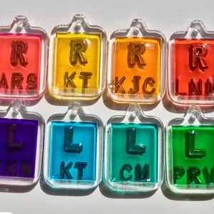 May include: Eight colorful plastic eye chart squares with letters and numbers. The squares are arranged in two rows of four. The top row is red, yellow, orange, and red. The bottom row is purple, blue, green, and green.