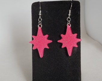 May include: A pair of pink glitter star-shaped earrings with silver hooks.