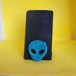 Broche de cabeza alienígena en resina verde azulado
