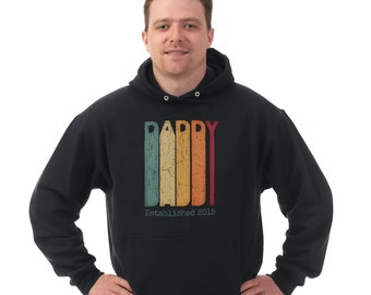 May include: Black hooded sweatshirt with a vintage-style graphic that says "Daddy Established 2015" in colorful stripes.