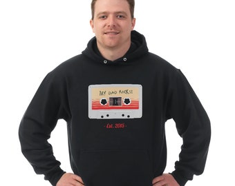 May include: Black hooded sweatshirt with a graphic of a vintage cassette tape with the text "My Dad Rocks! - Est. 2015 -" printed on the front.
