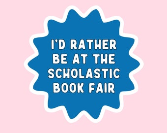 May include: A blue starburst sticker with white text that reads "I'd rather be at the Scholastic Book Fair."