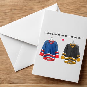 May include: A white greeting card with a matching envelope. The card features illustrations of two hockey jerseys, one blue and one black, with the text "I would come to the cottage for you."