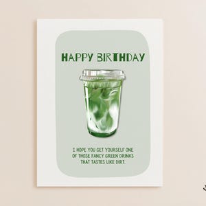 May include: A greeting card with the words "HAPPY BIRTHDAY" in green. It features an illustration of a green drink in a clear plastic cup. The text below reads, "I HOPE YOU GET YOURSELF ONE OF THOSE FANCY GREEN DRINKS THAT TASTES LIKE DIRT."