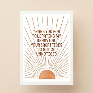 May include: A rectangular greeting card with a white background featuring a copper-coloured sun graphic at the bottom with radiating lines. The text reads: THANK YOU FOR TOLERATING MY BEHAVIOR. YOUR SACRIFICES DO NOT GO UNNOTICED in brown lettering.